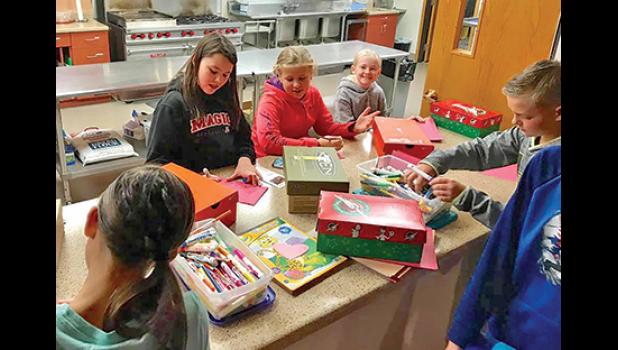 YOUTH AT REJOICE LUTHERAN CHURCH (R) write handwritten messages to include in their Operation Christmas Child shoeboxes.