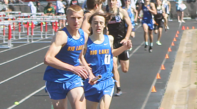 Owen Layton takes the baton from Jack Leuer in the 4x800 relay at the Section 5AA meet last week. The team set a new school record of 8:04.89 and will represent Big lake at the state meet this weekend. (Photo by Ken Francis.)