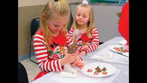 SOPHIA PRATT WATCHES HER SISTER, CLARA as she concentrates on creating the perfect snowman treat during Becker Community Center’s Cooking with Mrs. Claus event last Saturday. (Photo by Penny Leuthard)