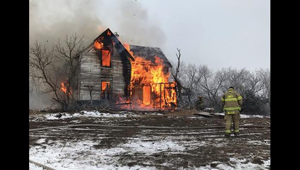 A firefighter watches as the old farmhouse becomes fully-engulfed in flames. (Submitted Photo.)