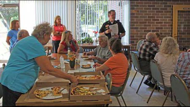 BECKER POLICE CHIEF BRENT BALOUN (R) shared information on keeping one safe to a large gathering of interested seniors at Woodbriar Senior Housing Tuesday evening. The residents were served pizza from Big D’s and Baloun — along with members of the fire department (not shown) and Council Members Tracy Bertram (L) and Lori Keller — fielded questions and comments from the mass.