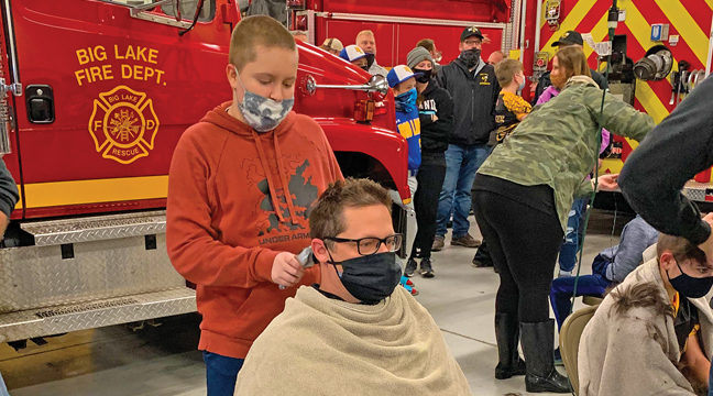 COLTON ANDERSON got out the clippers and shaved the head of his sixth grade football coach, Cary Schaller. Dozens of kids, friends, family members hsowed their support of Colton by shaving their heads Monday at the BL Fire Station. (Patriot Photo by Bill Morgan)