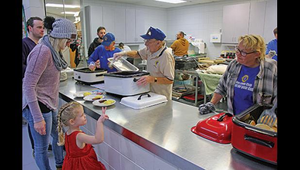 THIS LITTLE YOUNGSTER (L) told the Lions volunteer she wanted “two pancakes” for breakfast Saturday morning. The Lions had numerous volunteers on hand to serve food during the Breakfast with Santa event at the BCC. 