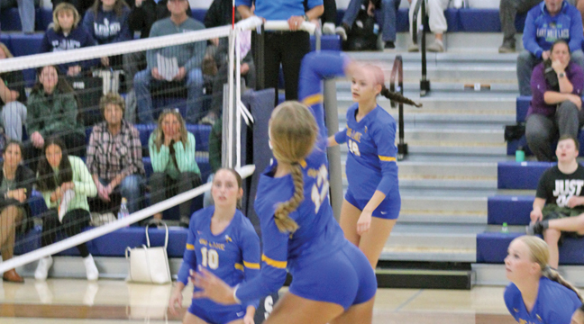 Madison Reed (#12)  attacks the net, covered by Kam Tschritter and Iva Sanchez. (Submitted Photo).