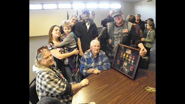 JOHN PERSHING OLSON (CENTER) posed for photos with family and a display of his medals and a photo of Olson when he served in the Army in the 1940’s. (Submitted Photo)