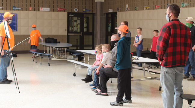 CHRIS MCKELLIPS OF PARTY CRASHERS RC RACING (FAR LEFT) demonstrated how the remote control cars work to a group of Becker kids and parents. (Photo by Katherine Cantin.)