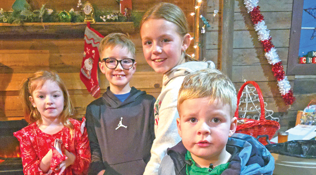 Lucy Bjorlin, Nolan Baune, Brynlee Baune  and Leo Bjorlin enjoyed their extended time at the Farm Friends Santa at the Barn event Monday. (Photo by Mary Nehring.)