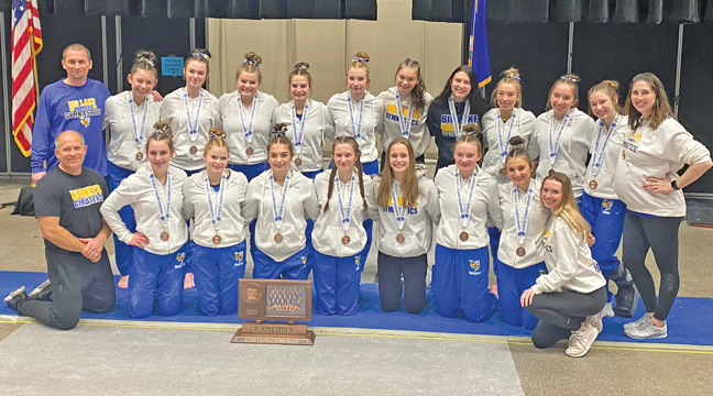 THE 2022 BIG LAKE GYMNASTICS TEAM posed with their coaches and the third place trophy following competition at the state tournament in Minneapolis last weekend.  (Submitted Photo).