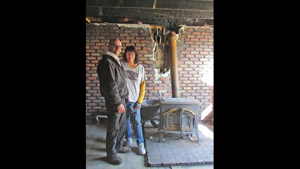 ANDI AND MARIANE HOEHN with the woodstove they use to heat their home and where the fire first started. (Photo by Penny Leuthard)