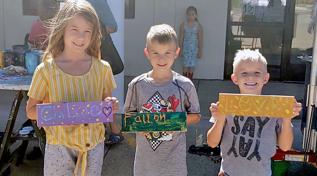 MOBILE SIGN SHOP. Local libraries will be bringing back the “mobile sign shop” that was popular last year. This archive photo shows three siblings showing off their hard work from last year’s mobile sign shop. (Patriot archive photo.)