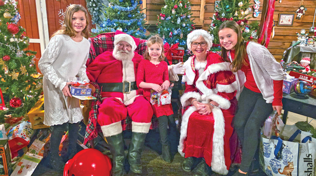 Allison, Charlotte and Haley Lieser of Foley posed with Mr. & Mrs. Santa Claus at the Farm Friends event Monday night. (Photo by Mary Nehring.)