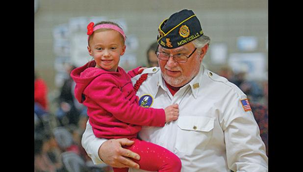 VIETNAM VETERAN LUKE TORRELL carried his granddaughter, Alayna, to their seats at Monday’s Veteran’s Day program at the Primary School. Torrell is a member of the Monticello Legion but practices with the Becker Legion Color Guard and has family that live in Becker. (Photos by Bill Morgan).