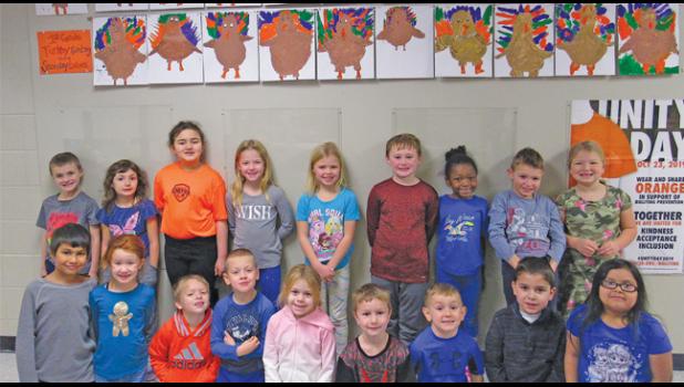 FIRST GRADERS FROM PROFESSORA LUCIA’S class pose with the colorful turkeys they made in Anna Barton’s art class. (Photo by Penny Leuthard)