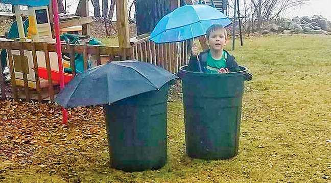 Cade Kuphal wasn’t daunted by the rainy weather at his home near Palmer last week. He took shelter in an empty garbage can. (Submitted photo). 