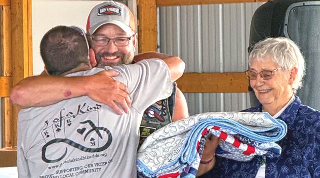 DAVE PEDERSON presents Cyle Paumen a Quilt of Valor for his service, Paumen’s mom Lila Paumen standing proudly next to him. (Submitted Photo).