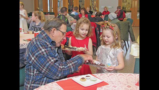 EMMY HECKMANN AND GRACE MAILE serve treats to guests at Rejoice’s European Christmas Coffee and Bake Sale on Saturday. (Photo by Penny Leuthard) 