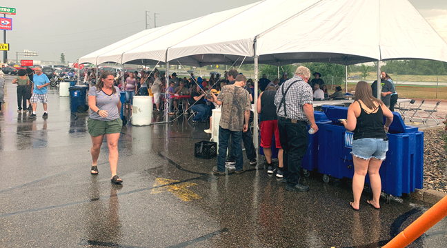 A SUDDEN RAIN SHOWER sent guests (above) under the canopies but didn’t stop the fun. (Photo by Penny Leuthard.)