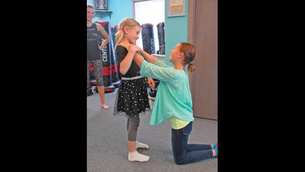 MYA AND MCKENNA BENSON demonstrate some of the moves they learned during Sunday’s self defense class. (Photo by Penny Leuthard)