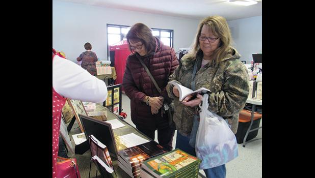 PAT ROELIKE AND BARB HAACK look through author Cynthia Frank-Stupnik’s book selections during the Clearwater fall craft and vendor event last Saturday. (Photo by Penny Leuthard)