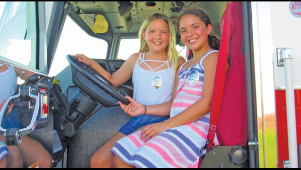 LUCY MILLER AND NEVAEH SULLIVAN pose inside a Becker Fire Dept. fire truck during Night to Unite. (Photo by Penny Leuthard)