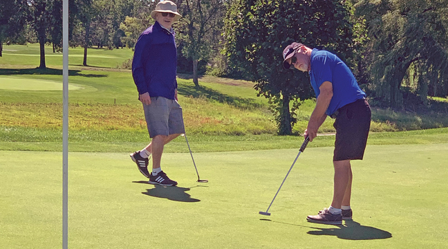 DAVE MORGAN of the Morgan Brothers foursome, sent this putt towards the hole while brother Tim (L) looked on. The Morgans finished at -9, good enough for third place at the GRFIA tournament at Pebble Creek Monday. (Photo by Bill Morgan).