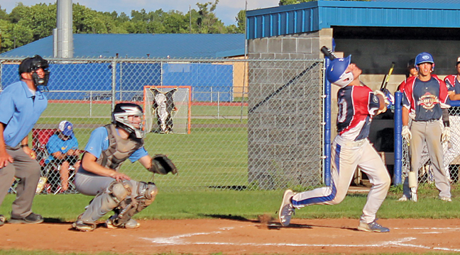 Big Lake’s Samson Schlegel follows through after hitting a fly ball in this at-bat Tuesday evening.  Looking on is Becker catcher Noah Mohs. (Photo by Mark Kolbinger).