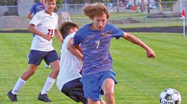 Ryler Peterson fights off a defender for possession in a game earlier this season. Peterson had goals against North Branch and Cambridge-Isanti. (Photo by Ken Francis.)