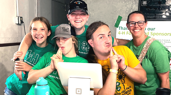 NORTHERN PEAK 4-H MEMBERS Kendra and Ashley Wolff, Isaac Wagner, and Kiley and Karen O’Konek have some fun during their club’s turn running the 4-H food building Saturday morning.(Submitted photo.)