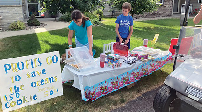 Avery Rambow and Adam Siemens  of Clearwater are selling lemonade and cookies to help save planet Earth’s oceans. They set up their stand on June 17 in Clearwater Estates. (Submitted Photo).