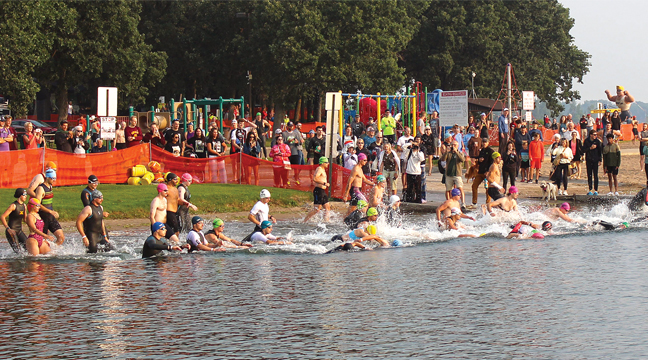 Athletes from the Olympic Division  take off from the beach at Lakeside Park to start the 2025 Big Lake Graniteman Triathlon. (Photo by Ken Francis.)
