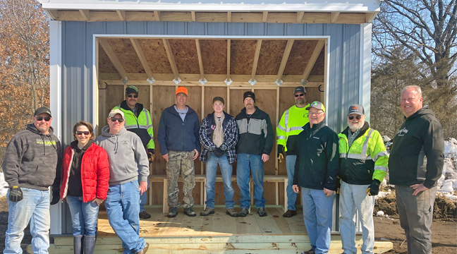 Sherburne County snowmobilers will have a new source of sanctuary to get out of the wind next winter thanks to an industrious Boy Scout, Alex Rolloff, who took on the project to fulfill the requirements as he worked towards his Eagle Scout honor. Alex had plenty of help with the final delivery of the shelter, from left, Jamie Hinton, Jennifer Rolloff, Jason Hendrickx, Joe Dwenger, Eric Hirsch, Alex Rolloff, Eric Rolloff, Mike Johnson, Larry Gallus, Gordy Johnson and Pete Ewing. (Photo by Mark Kolbinger).
