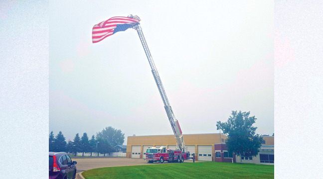 AS PART OF THEIR ANNUAL TRIBUTE to America and the victims of 9-11, the Becker Fire Dept. displayed a huge flag on one of their ladder trucks along Bank Street in Becker Thursday. (Patriot Photo by Mary Nehring).