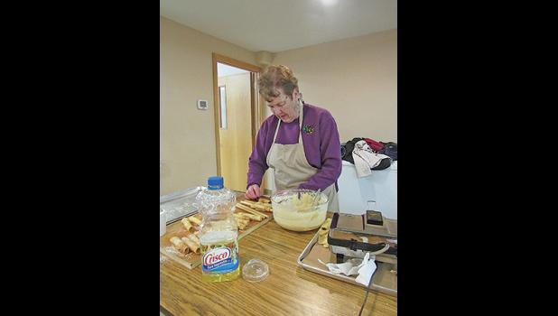 EVIE PETERSON demonstrates the intricacies of krumkake making during St. Luke’s Craft and Cookie Stroll. (Photo by Penny Leuthard)