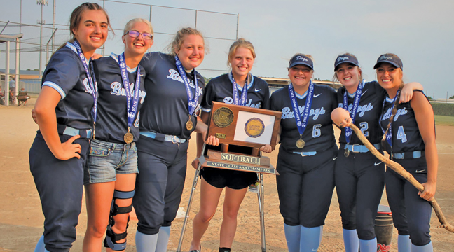 The seniors on the Becker Bulldog softball team posed for a picture with the state title trophy.  Brooke Hendrickson (R) holds the team’s good luck charm, purportedly named “A-a-ron” (Submitted Photo).