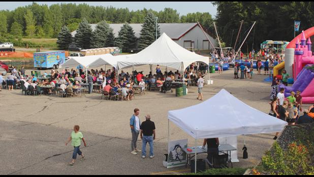 CLEARWATER HERITAGE DAYS activities moved its location from the shopping plaza parking lot this year. Family Fun Night took place in the Driftwood Golf Course parking area, while the parade moved to Main Street. Above, people gathered in tents to share the traditional Lions brat and corn on the cob meal, while kids played on the inflatable games and bungee trampoline. (Photos by Ken Francis).