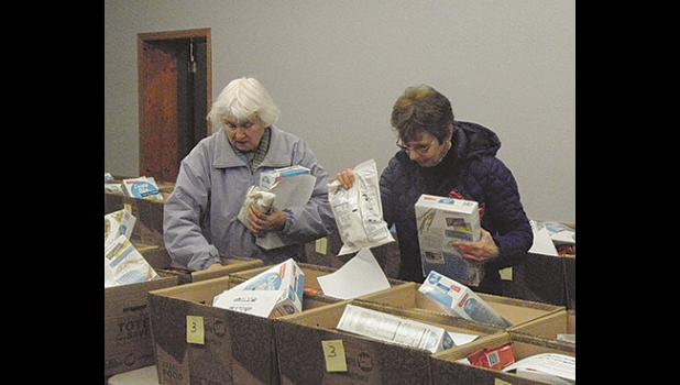 Volunteers Barbara Potter (left) and Dianne Stute help put together Thanksgiving baskets Monday morning at the Clearwater-Clear Lake Food Shelf. (Photo by Ken Francis.)