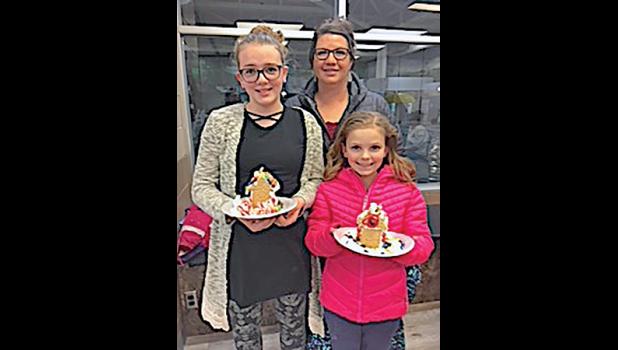 LILY AND MAGGIE WILHELM, along with their mom, Amanda, show off their completed gingerbread houses. (Submitted Photo)