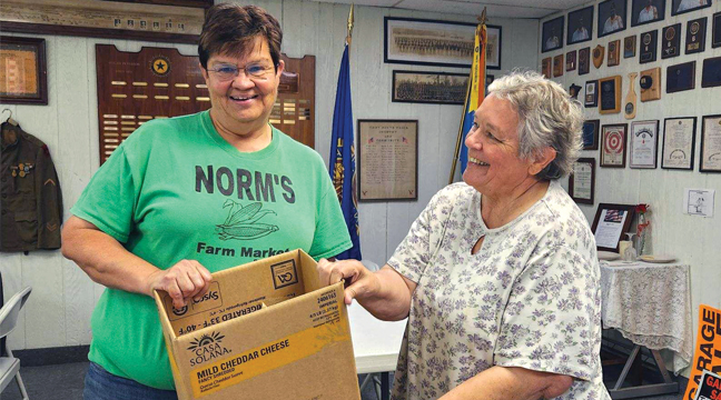 Jean Johnson (left)  was doing the “cooking” for her army of farmers at home, as she loaded up an entire box of taco lunches with the help of Legion Auxiliary member Paula Hinds. (Patriot Photo by Mary Nehring).