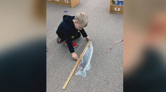 AFTER CATCHING HIS FISH, Aaron Beck demonstrates how to measure it. (Photo by Penny Leuthard.)