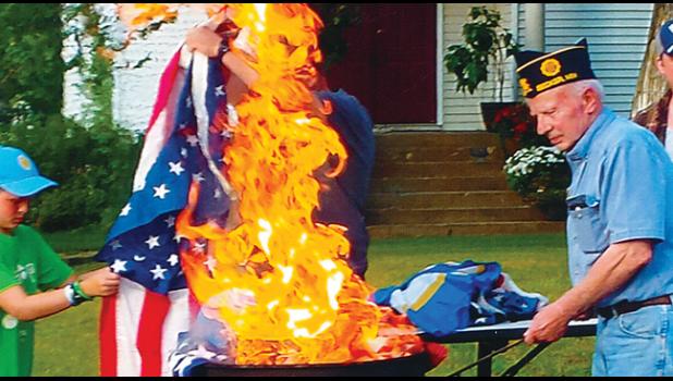 Above, Fred Kleine prepared a flag for burning,  assisted by family members of Becker Sons of the American Legion. Commander John Riebel began the ceremony, reading about the history of flag burning, Assisting were Chaplain Tim Hinds, Sgt. At Arms Bill Smith and 1st Vice Roger Bigalke. The Legion holds flag burning ceremonies regularly. Over 100 flags were disposed of Wednesday. Residents are asked to bring their flags to the Legion or to Becker True Value for proper disposal. (Submitted Photos)