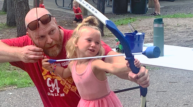 FIVE-YEAR OLD CLAIRE DUSTIN gets a helping hand during Scout Day at Warner Park. (Photo by Penny Leuthard.)