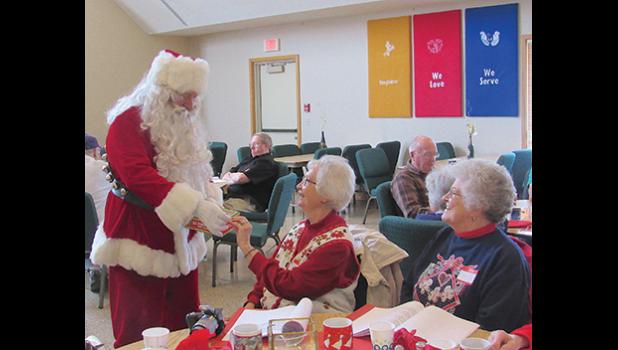 Santa hands out candy canes to Elaine Paumen and Joan Jendro at the Young at Heart event last year. (Photos by Penny Leuthard)