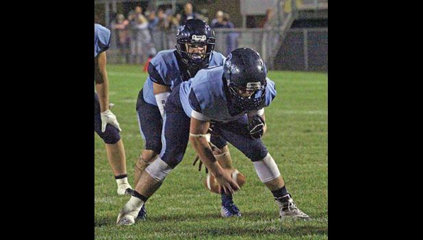 QB JOSH FOBBE takes the snap from center Carter Gustafson above. Fobbe helped the Bulldogs beat Rocori on the road Friday by throwing for three TDs — two to WR Kevyn Vilayphanh. (Photo by Bill Morgan).