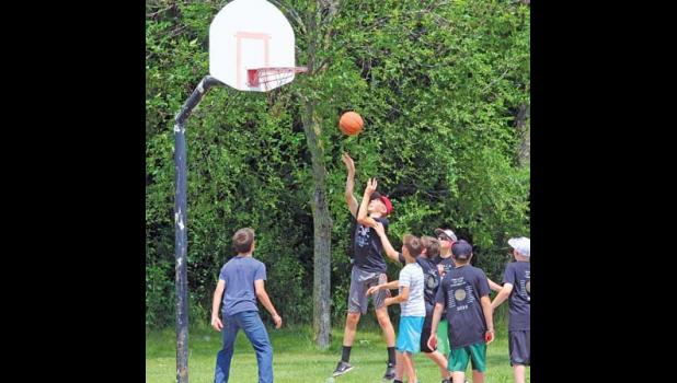 DOZENS OF YOUNGSTERS descended upon the community center backyard to play games, eat, drink and get athletic, just as these area youths on the basketball court in the parking lot.