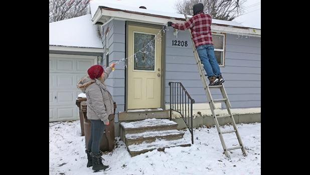 LEAH AND CALEB COX took advantage of Thursday’s milder temperatures to put up their Christmas lights on their home along Sherburne Avenue.