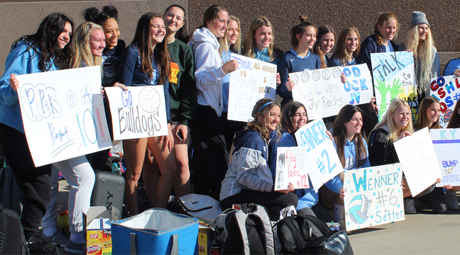 BECKER VOLLEYBALL’S JV AND VARSITY TEAMS posed for a photo holding the signs made by their supporters. (Photo by Katherine Cantin.)