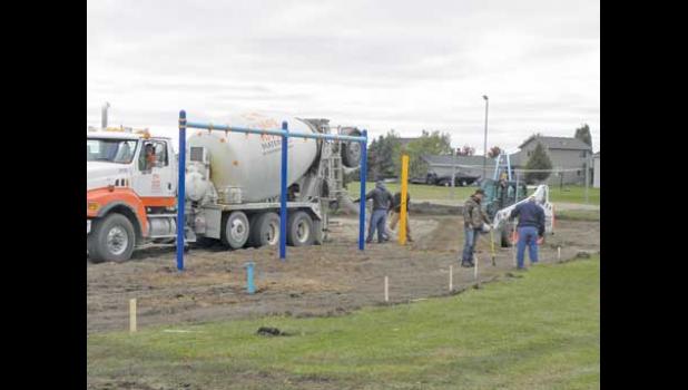  A crew from Landscape Structures began erecting the swing set at Eldorado Park Wednesday as the first stage of the playground area, while Robbie Kottke and Jack Helget of the Clearwater maintenance staff (at right) set stakes for the concrete perimeter curb. 