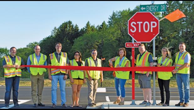 CITY STAFFERS AND COUNCIL MEMBERS (L) held a ribbon-cutting ceremony celebrating the opening of Energy Drive through the Business Park in Becker.  Left to right: Chris Lisson, Greg Pruszinske, Rick Hendrickson, Rebecca Stanfield-Olmscheid, Mike Doering, Mayor Tracy Bertram, Troy Cox, Marie Pflipsen and Phil Knutson. (Submitted Photo)