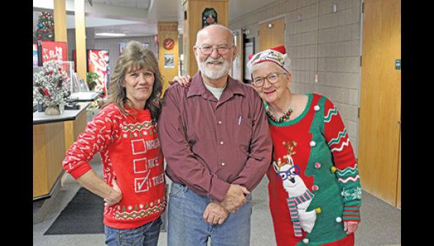 NELLIE-JO SIMPSON, JOHN REIBEL AND LIPPY LU SCHUETTE posed for a photo outside the doors to the gym as they greeted visitors attending the Christmas Day dinner Tuesday. 