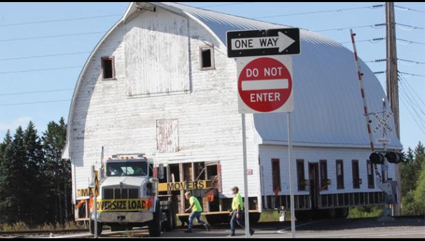KUDOS TO THE TRUCK DRIVER who had to maneuver the barn over the railroad tracks and through the medians and signs to gain access to Hwy. 10 in late September. (Photo by Bill Morgan).